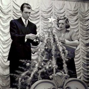 Main leads of the movie decorating a Christmas tree, looking confused